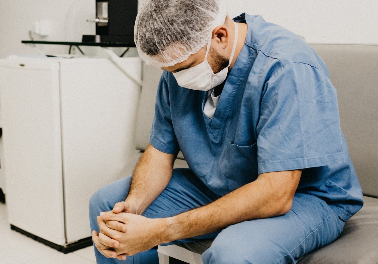 man-wearing-blue-scrub-suit-and-mask-sitting-on-bench-3279197 (1)